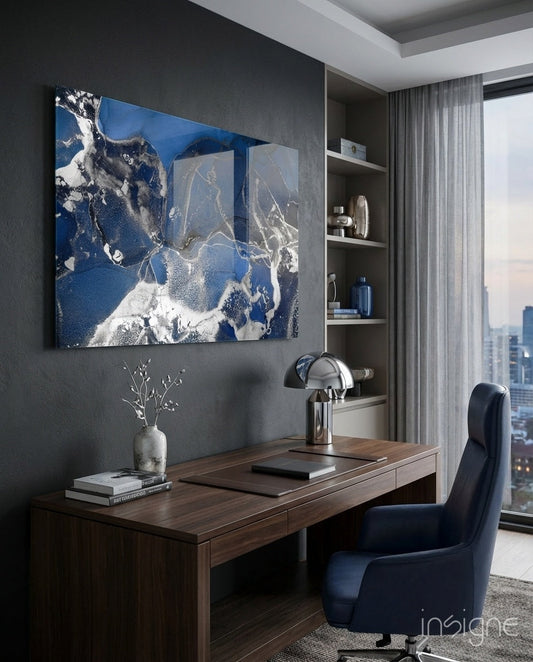 Royal blue and white abstract glass wall art displayed above a wooden desk in a modern office workspace with city views.