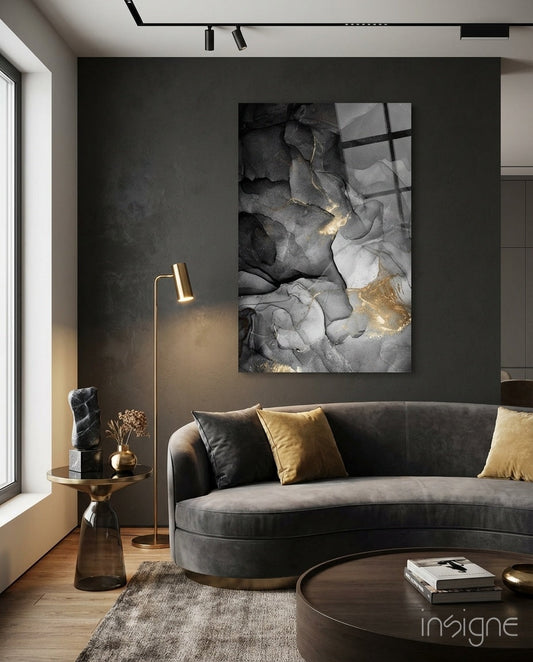 Charcoal Black Gold Ink Glass Wall Art displayed above curved gray sofa in modern living room with gold accents and dark feature wall.