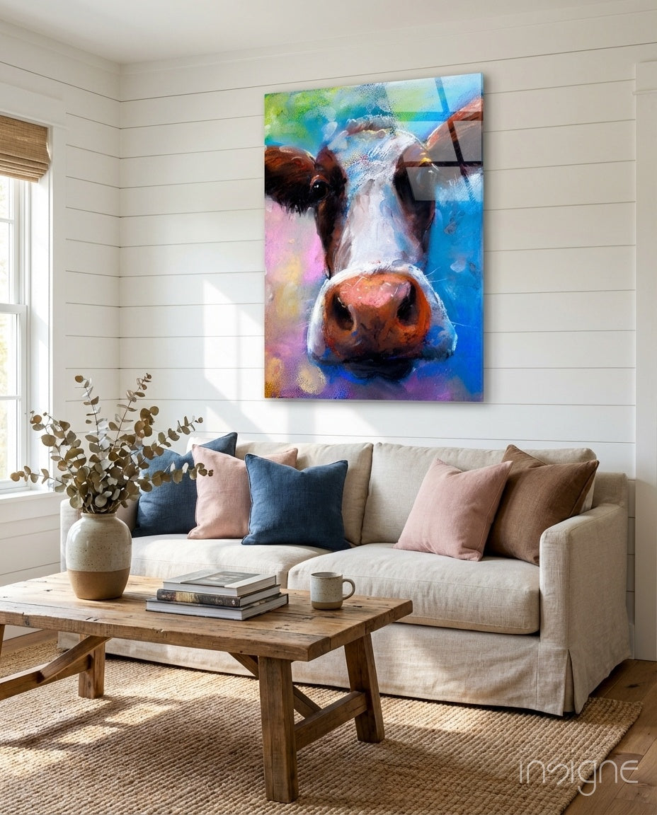 Colorful cow glass wall art hanging above a cream sofa in a bright living room with wooden furniture.