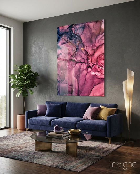Magenta pink ink bloom glass wall art displayed above a navy sofa in a modern living room setting.