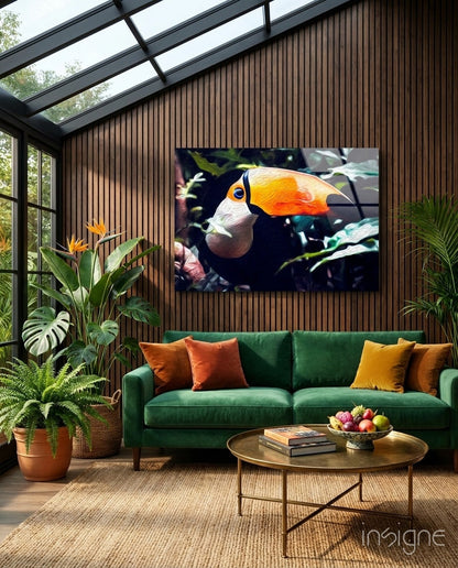 Toco Toucan glass wall art displaying a colorful bird with orange beak and white head mounted above a green velvet sofa in a modern sunroom.