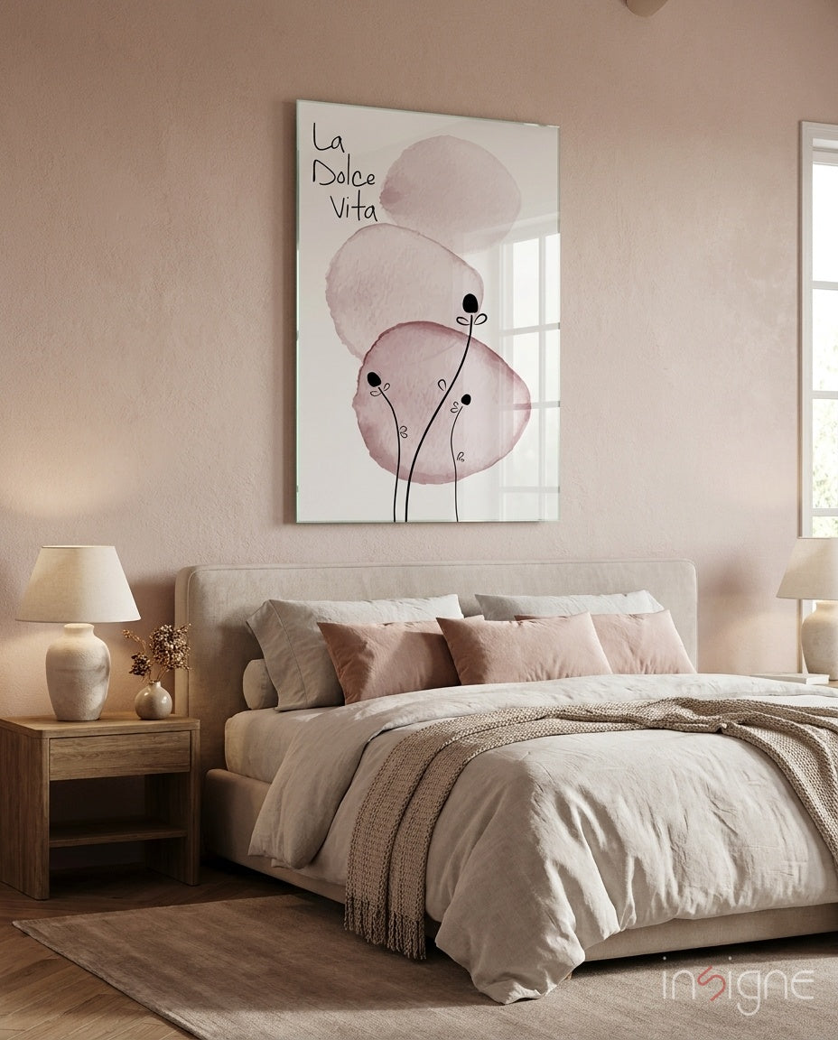 La Dolce Vita glass wall art displaying watercolor circles in muted pink tones with linear botanical elements, hung above a bedroom bed.