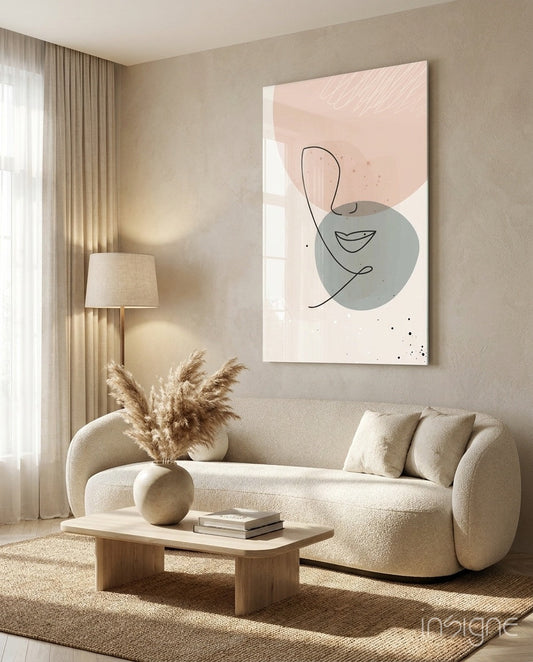 Blush Grey Circle Line Face Glass Wall Art displayed above a cream curved sofa in a minimalist beige living room interior.