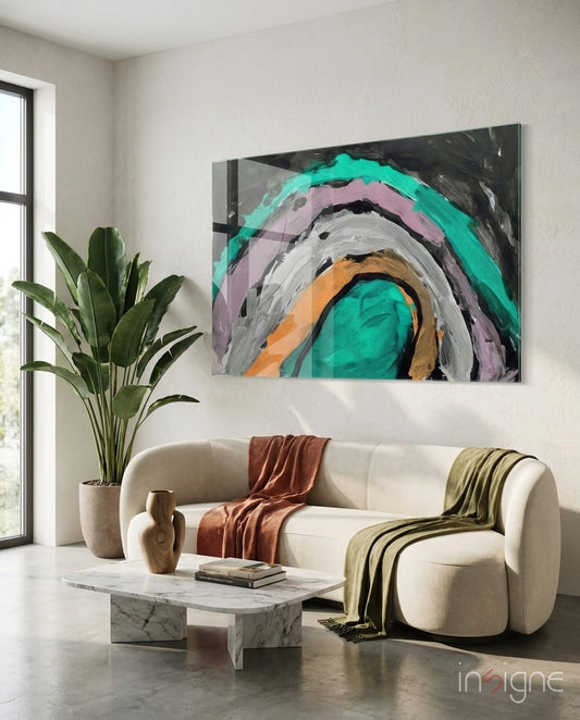 Abstract glass wall art with concentric circles in turquoise, pink, orange, and gray displayed above a cream sofa.