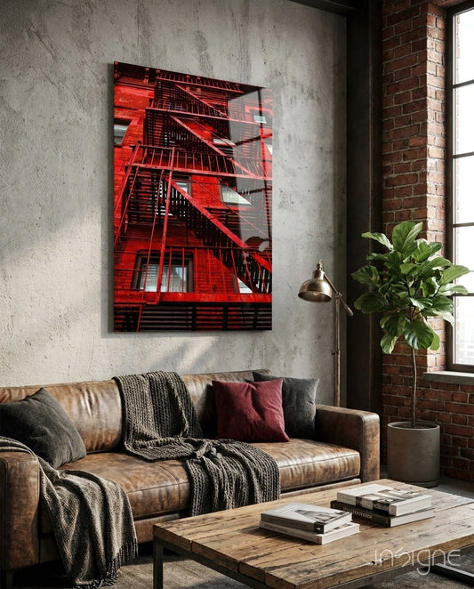 Red Stairs glass wall art displayed above a tan leather sofa in an industrial loft interior with exposed brick.