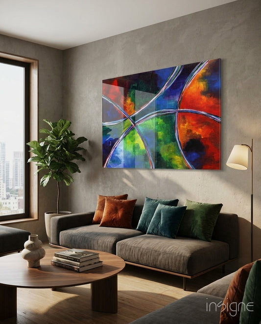 Colorful abstract glass wall art with interlocking ribbons in red, blue, green, and orange displayed above a gray sofa in a modern living room.