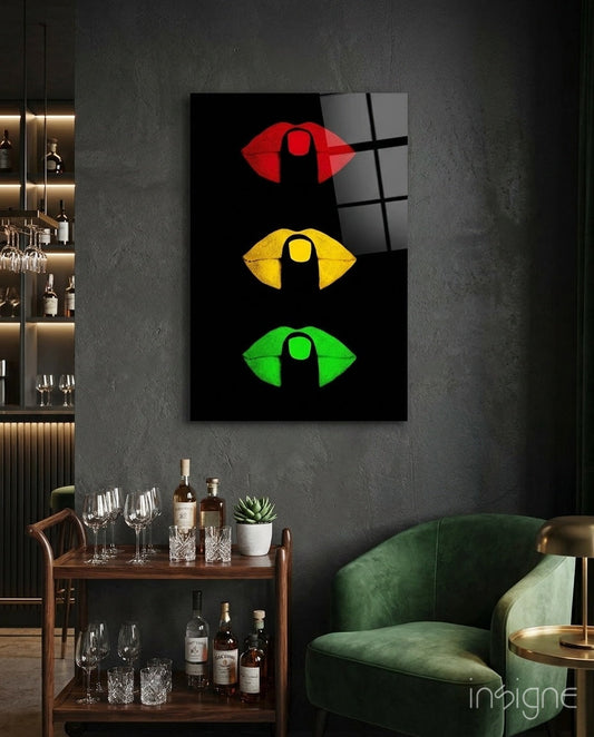 Traffic light lips artwork hung on dark gray wall above wooden bar cart and green velvet chair in modern lounge setting.