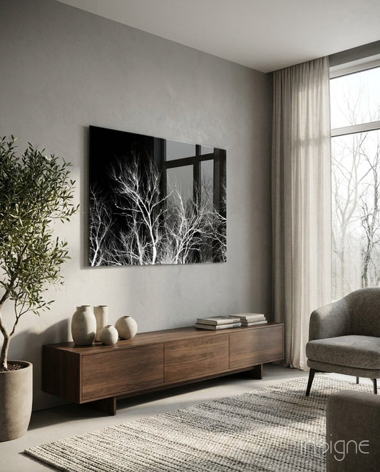 Black and white tree branches wall art displayed above a wooden dresser in a minimalist living room with gray furnishings.