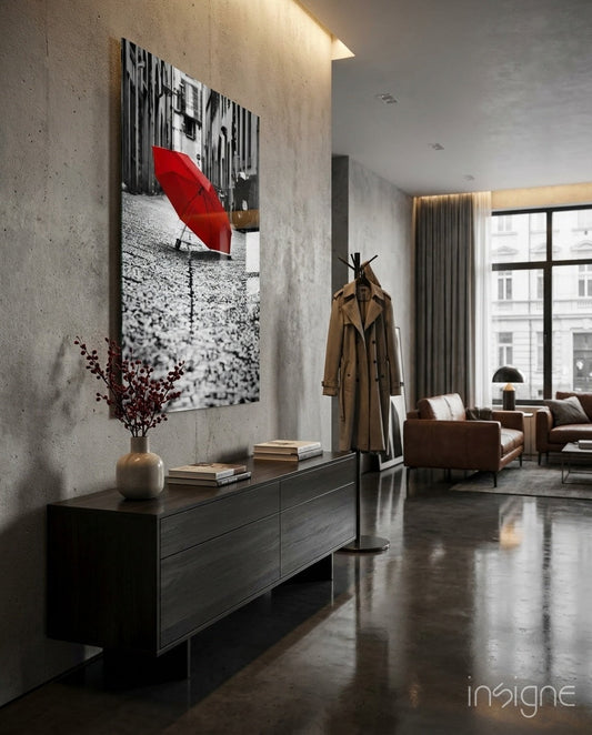Black and white photograph with red umbrella displayed on concrete wall above dark dresser in modern apartment interior.