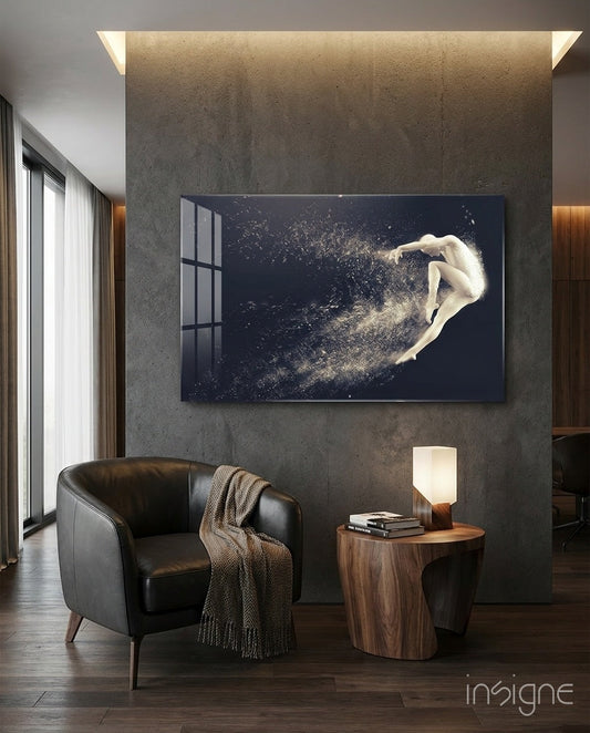 Modern living room with leather armchair, wooden side table, and large dark glass artwork depicting a pale figure dissolving into white particles mounted on concrete wall.