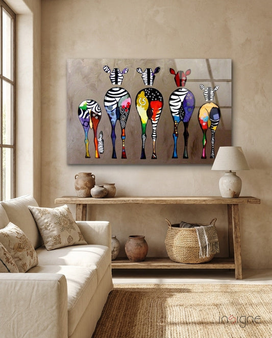 Colorful Zebras Glass Wall Art hanging above a wooden console table in a neutral beige living room with cream furniture and natural light from a window.