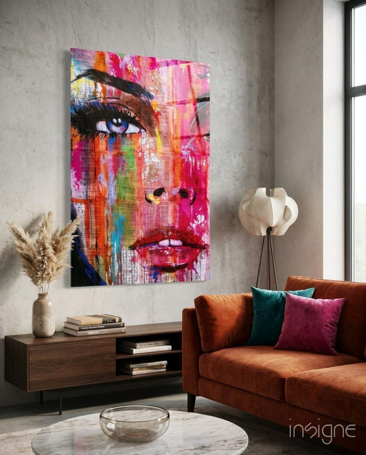 Colorful pop art face glass wall art displayed above a wooden console table in a modern living room with rust-colored sofa.