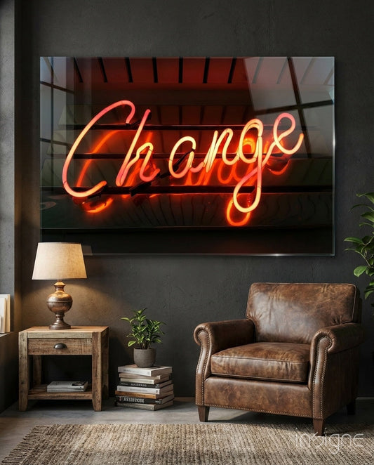 Neon "Change" sign in red and orange glowing script displayed on dark wall above leather chair and wooden side table.