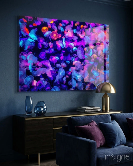 Neon jellyfish glass wall art in vibrant blue, purple, and pink displayed above dark furniture in a modern living room setting.