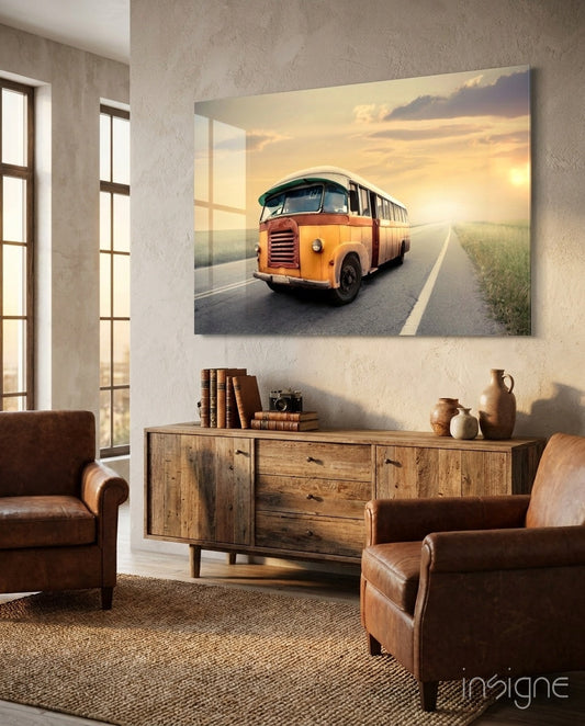 Orange vintage bus on sunny highway displayed as glass wall art above wooden sideboard in rustic living room.