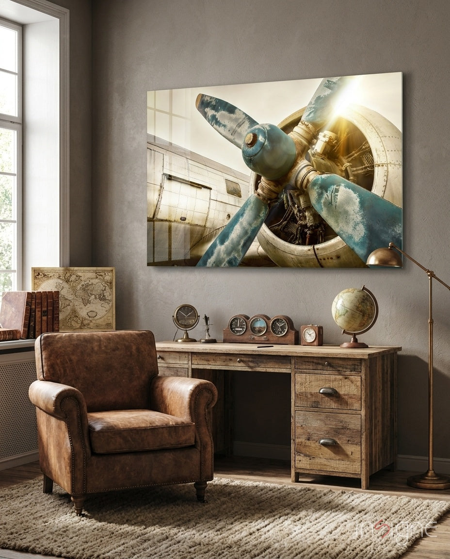 Vintage airplane propeller and engine in weathered blue and brass tones displayed above wooden desk in aviation-themed study.