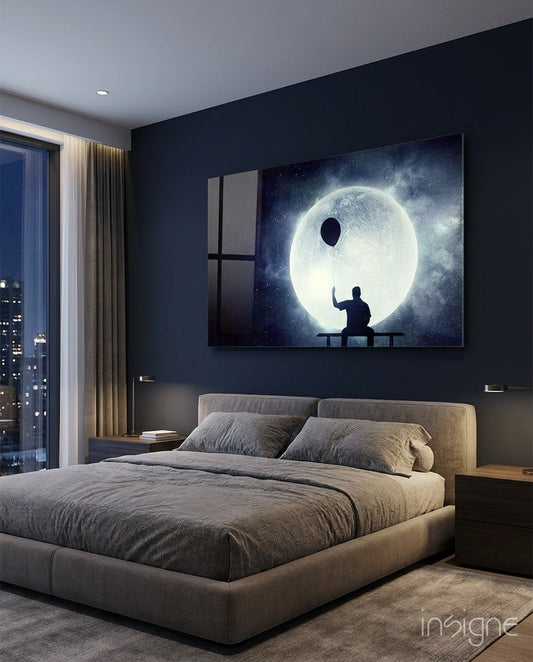 Glowing moon artwork displayed above gray bed in dark modern bedroom with city view.
