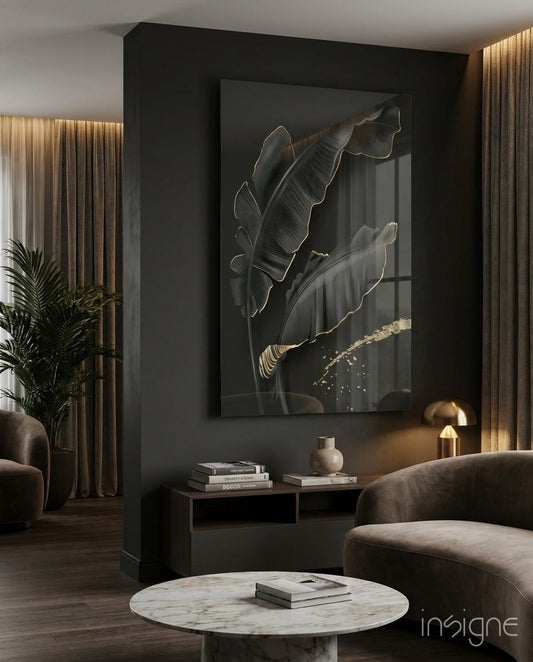 Golden-outlined black leaves glass wall art displayed above a black console table in a modern living room with dark furnishings and warm lighting.