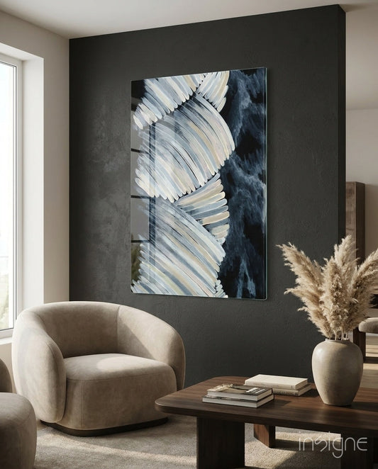 Cream feather wings navy glass wall art displayed above a beige armchair in a modern living room with dark charcoal walls.