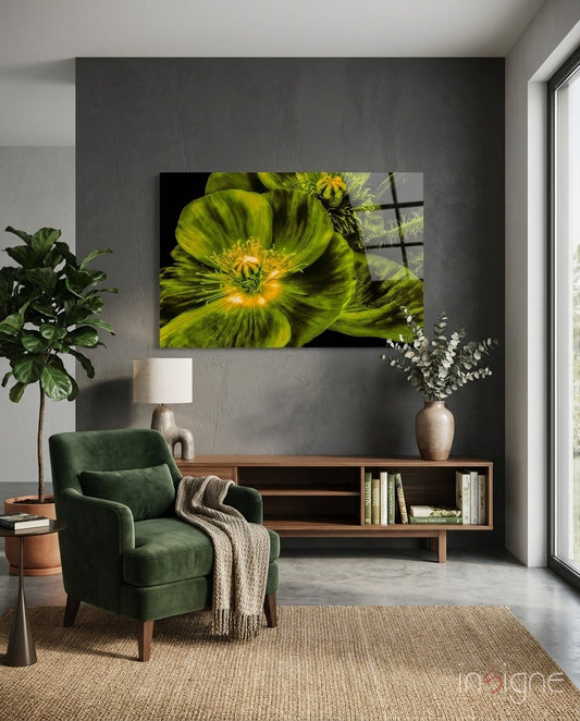 Glowing chartreuse poppy glass wall art displayed above wooden media console in modern living room with green chair and potted plants.