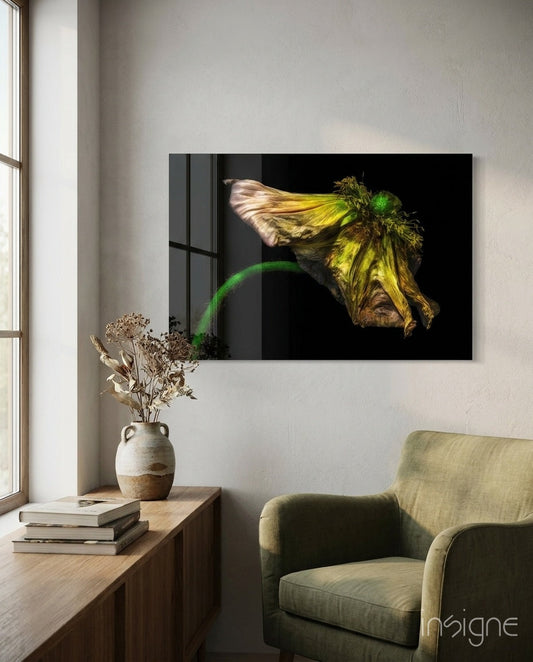 Wilting yellow poppy glass art displayed on white wall above wooden console table with dried flowers and books, olive chair visible below.
