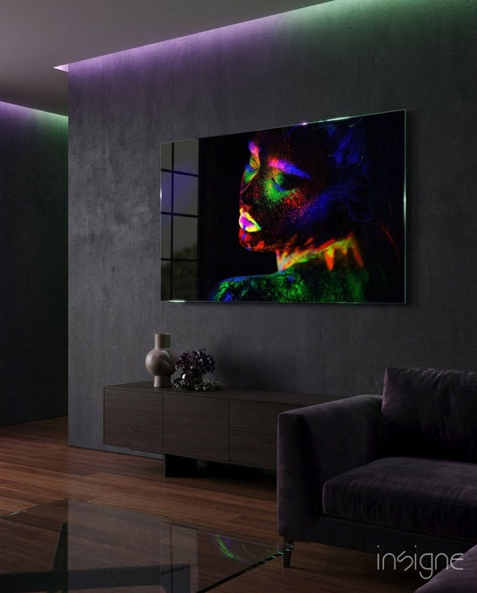 Modern living room with wall-mounted display showing colorful neon body art portrait against dark concrete wall.