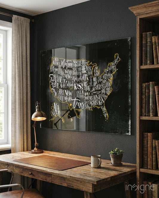 Gold-outlined USA map with state names on black glass panel mounted above wooden desk in dark-walled office.