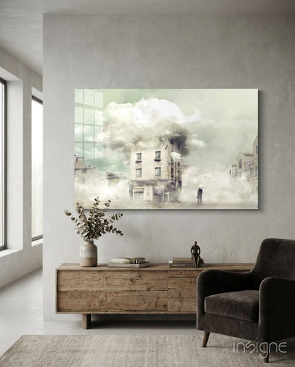 Mounted glass wall art depicting a misty street scene with a burning building, displayed above a wooden dresser in a minimalist interior.