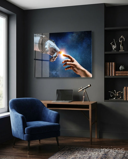 Creation Glass Wall Art depicting an astronaut's gloved hand reaching toward a human hand against a starry blue background, displayed above a wooden desk in a dark modern office.
