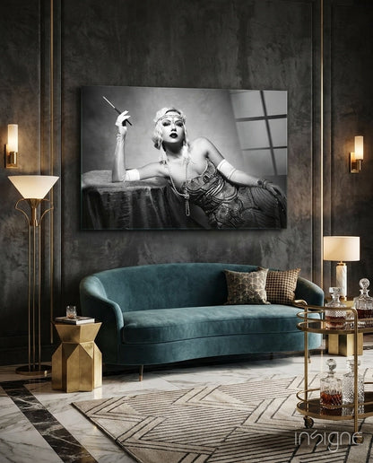 Black and white glass wall art depicting a glamorous 1920s woman with cigarette holder displayed above a teal velvet sofa in a luxurious interior setting.