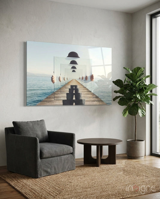 Surreal glass wall art depicting a wooden pier with layered mirrored panels, bowler hats, and ocean backdrop, displayed in a modern living room setting.