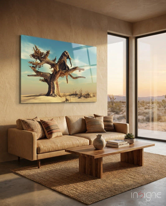 Glass wall art depicting an elephant on a gnarled tree in desert landscape, displayed above tan sofa in modern living room.