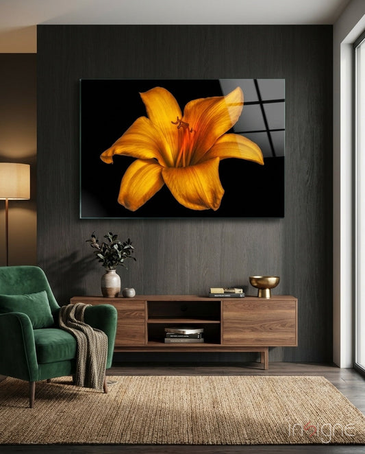 Golden orange lily glass wall art displayed above wooden media console in modern living room with green chair and beige rug.