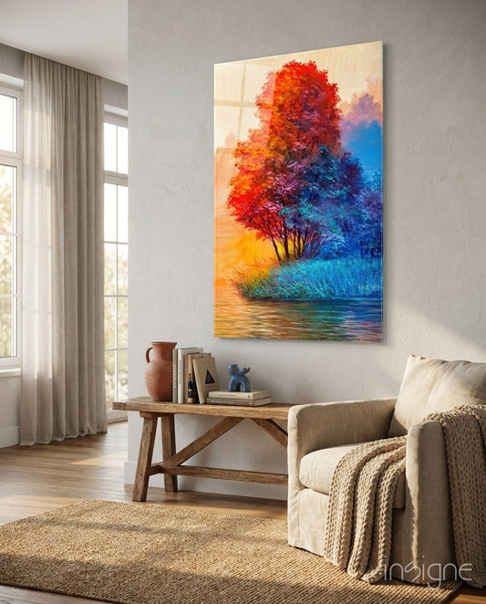 Colorful glass wall art depicting a red and blue tree by water displayed above a wooden console table in a modern living room.