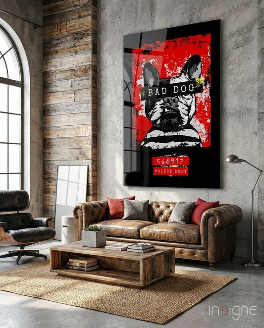 Bad Dog" glass wall art displaying a black and white dog with red background and police department text, mounted in industrial loft living room above leather sofa.