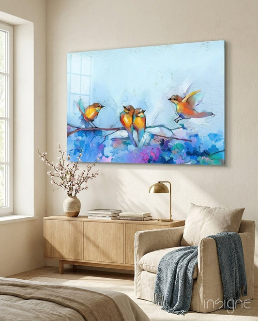Colorful glass wall art depicting three orange and yellow birds perched on a blue branch against a light blue sky, displayed above a wooden dresser in a bedroom.
