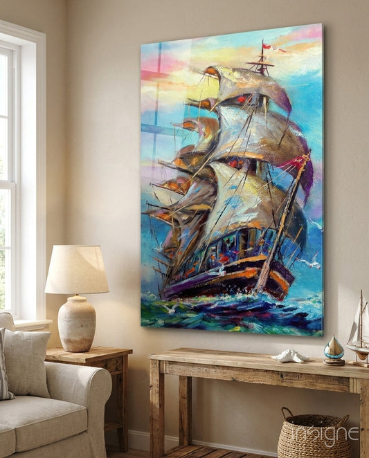 Colorful glass wall art of a sailing ship displayed above a wooden console table in a coastal-themed living room with neutral furnishings.