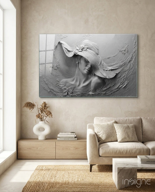 White relief glass wall art depicting a woman wearing a wide-brimmed hat, displayed above a wooden cabinet in a minimalist living room.