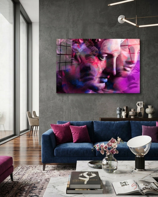 Magenta Grid Classical Bust Collage glass wall art displayed above a navy sofa in a modern living room with grey concrete walls.