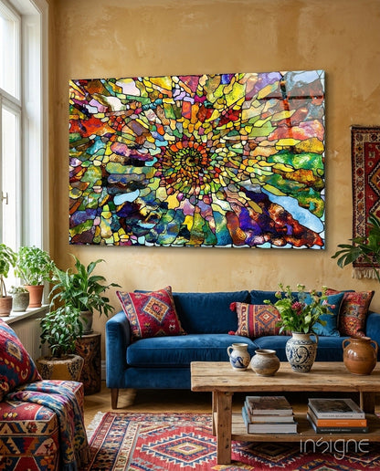 Colorful mosaic glass art with concentric spiral pattern in multicolored segments hanging above blue sofa in eclectic living room.