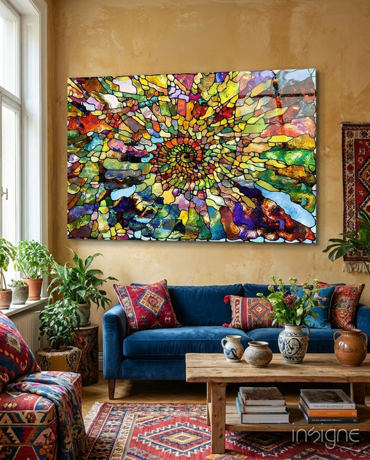 Colorful mosaic glass art with concentric spiral pattern in multicolored segments hanging above blue sofa in eclectic living room.