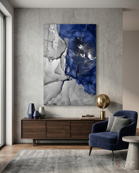 Blue and white marble glass art panel hung above wooden dresser in modern living room setting with navy chair.