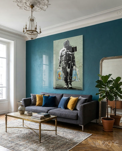 Modern living room with teal wall displaying Space Market Glass Art canvas of figure with blue and yellow accents above gray sofa.