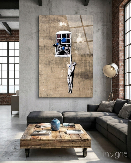 Contemporary loft interior featuring large Banksy-style canvas artwork with stenciled figures and blue window above charcoal sofa.