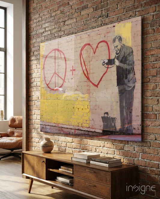 Graffiti Doctor Glass Art mounted on brick wall showing stenciled figure with red peace symbol and heart, yellow sections, displayed above wooden mid-century console table.