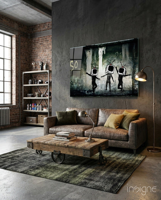 Dark street art style canvas with three black silhouette figures wearing TV head screens displayed above gray sofa in industrial loft setting.