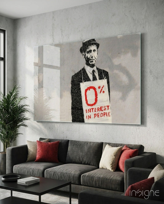 Modern living room with gray sofa displaying glass art print of man in suit holding sign reading "0% Interest in People.