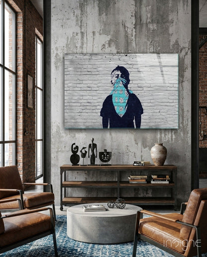 Street art style canvas depicting figure wearing turquoise bandana with skull pattern, displayed above wooden shelf in industrial loft setting.