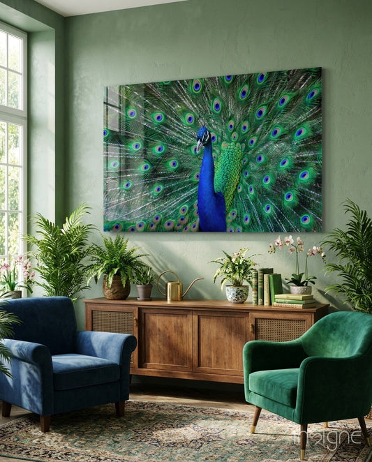 Peacock glass wall art displaying vibrant blue bird with green and teal feathers displayed above wooden cabinet in sage green room with plants and blue-green chairs.
