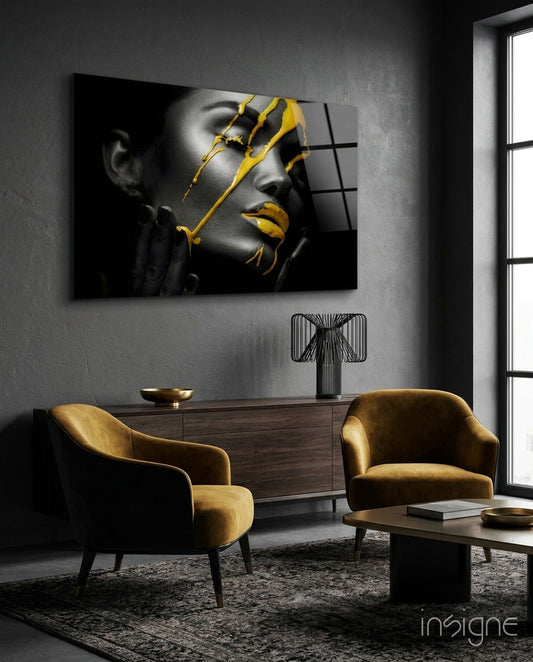 Yellow paint glass art depicting grayscale female portrait with gold accents displayed above wooden dresser in modern interior.